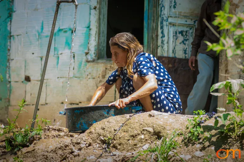 Woman Collecting Water Outside Home