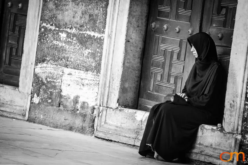 Woman in Black Abaya and Hijab Sitting in Doorway